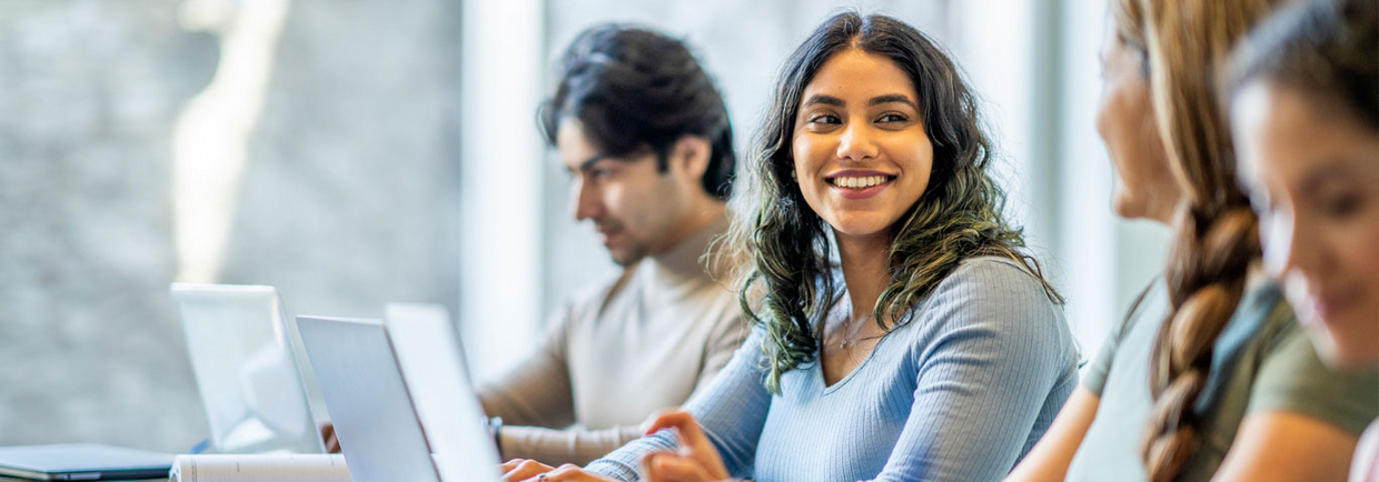 Studierende sitzen zusammen am Tisch und arbeiten an Laptops