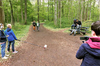 Ein Waldweg, auf dem Jungen mit Kamera und Mikro filmen